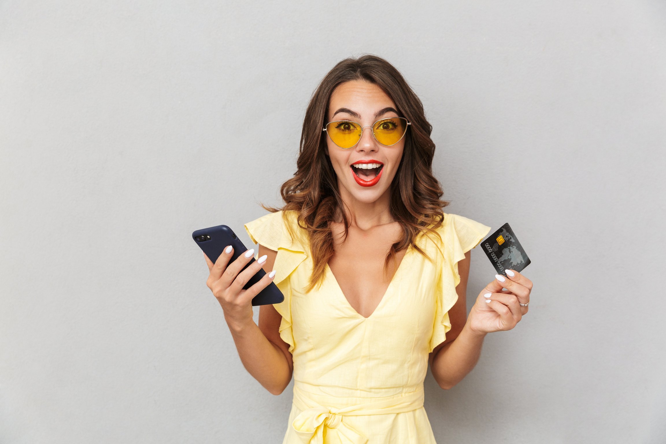 Excited Young Girl in Dress Holding Credit Card